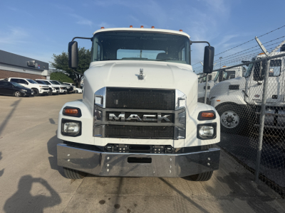 Truck front view of a white 2024 Mack MD6 hooklift showing large black grille with MACK logo and bumper, headlights, and side mirrors.