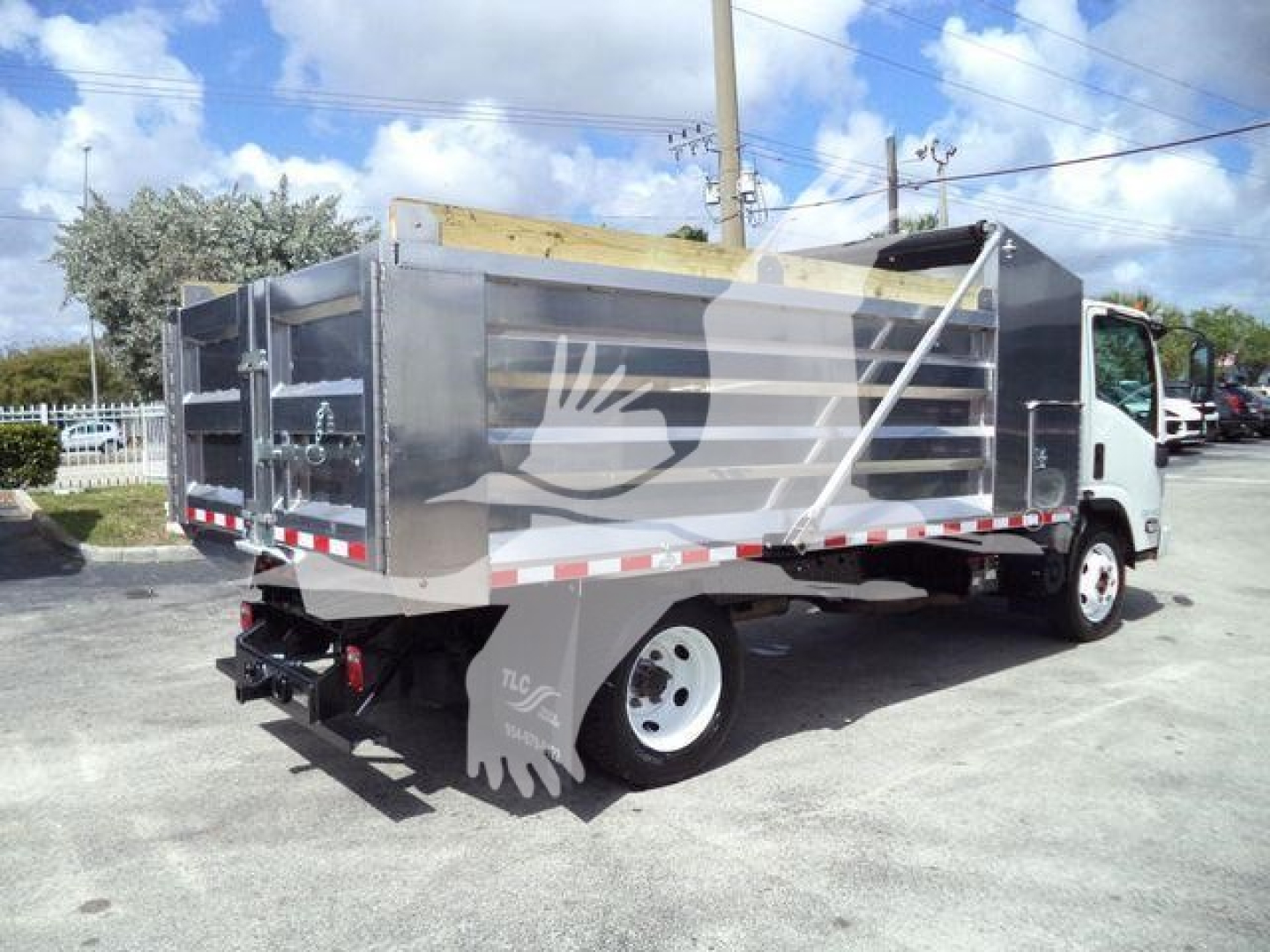 Isuzu NPR HD dump truck side view showing metal dump bed, rear hitch, and wheel.