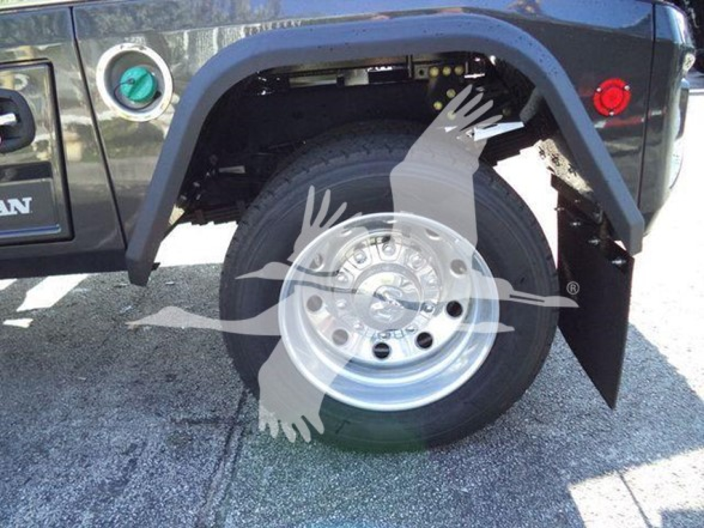 Ram 2026 Big Horn truck wheel and fender view showing wheel, fender flare, and partial body with green tow cap and red reflectors.