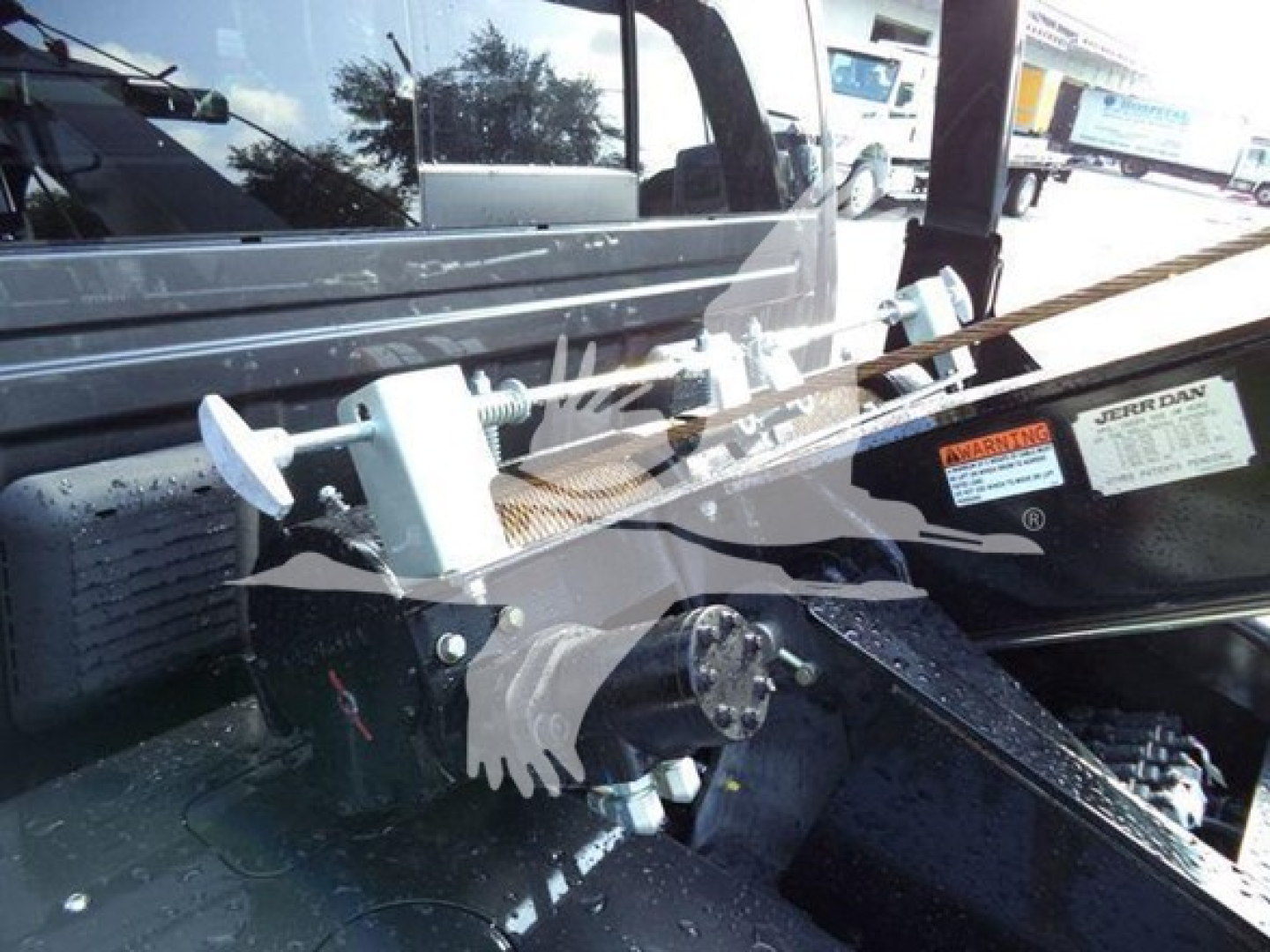 Winch system mounted in truck bed showing mechanical cable winch with protective housing and mounting hardware.