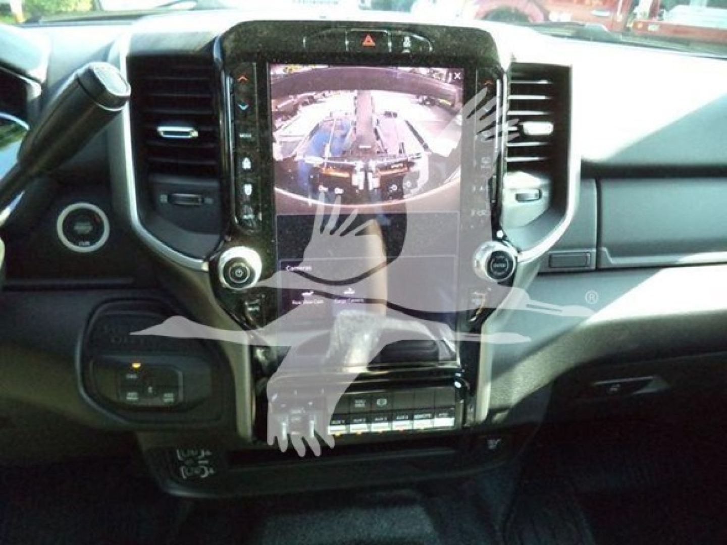 Dashboard view of a RAM pickup with large touchscreen display and gear shifter, interior center console visible.