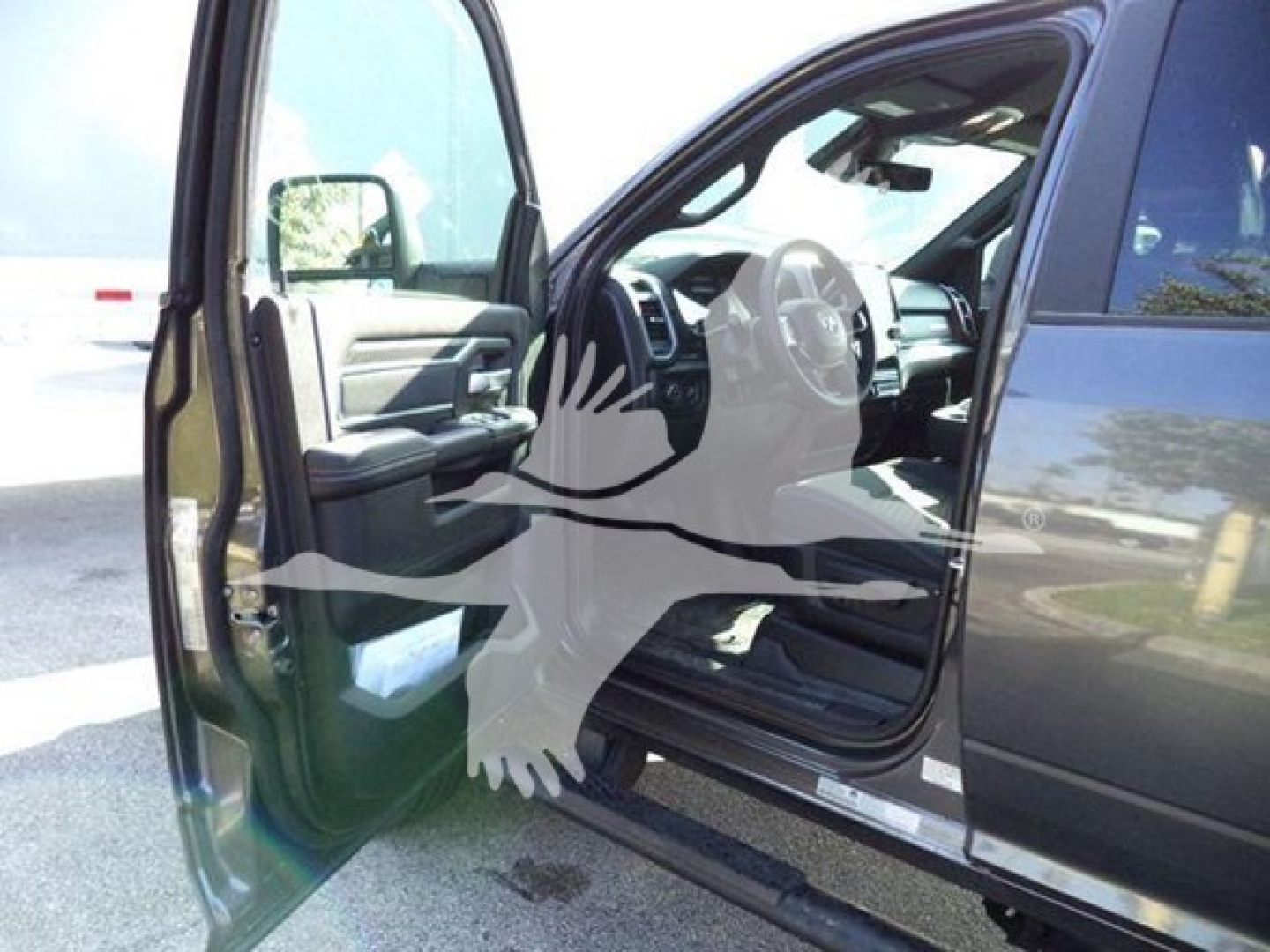 Ram driver seat and open front door showing interior of a 2026 Ram Big Horn truck with black exterior.