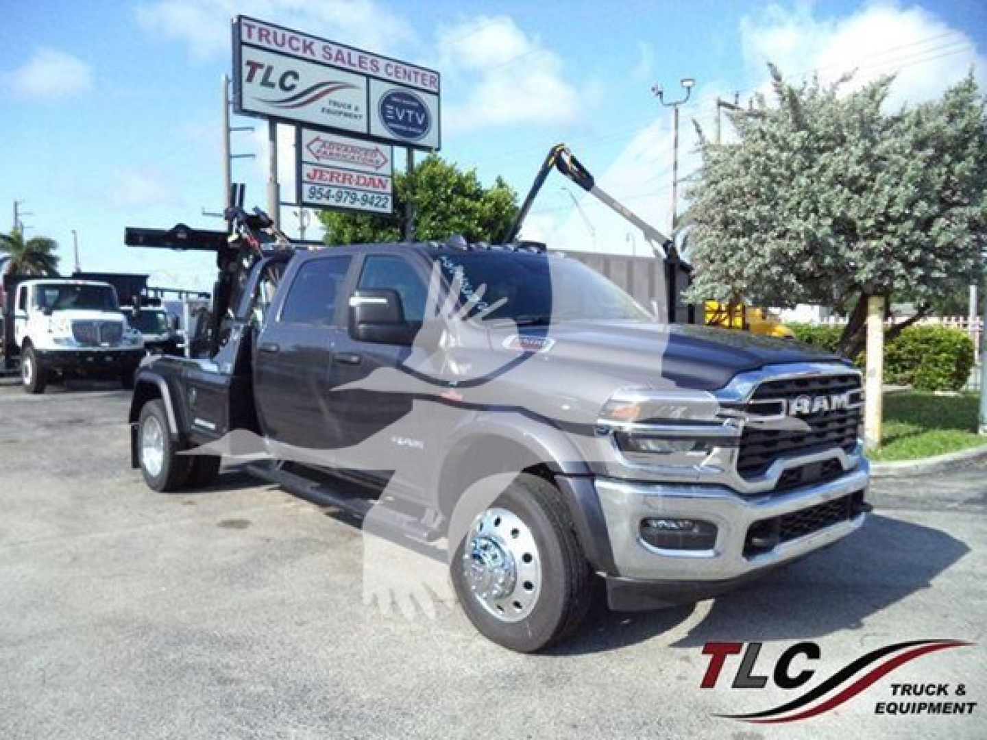 Ram 2500/3500 pickup truck in showroom lot with tow winch and crane attachment; RAM grille and front bumper; TLC Truck Sales Center sign in background; watermark overlay on image.