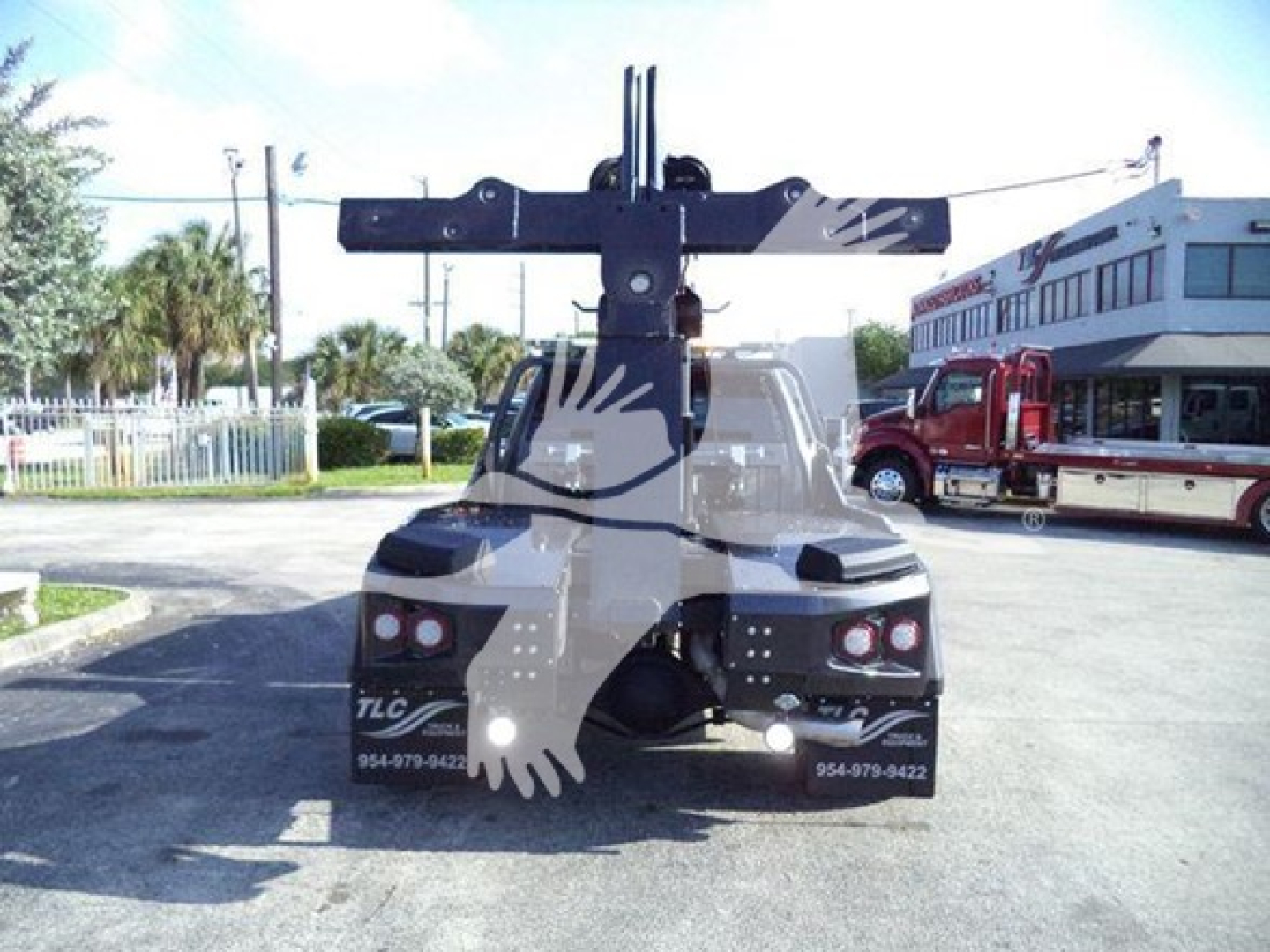 Ram truck bed with large winch and mounting kit visible from rear view, bumper and taillights, dealership lot in background.