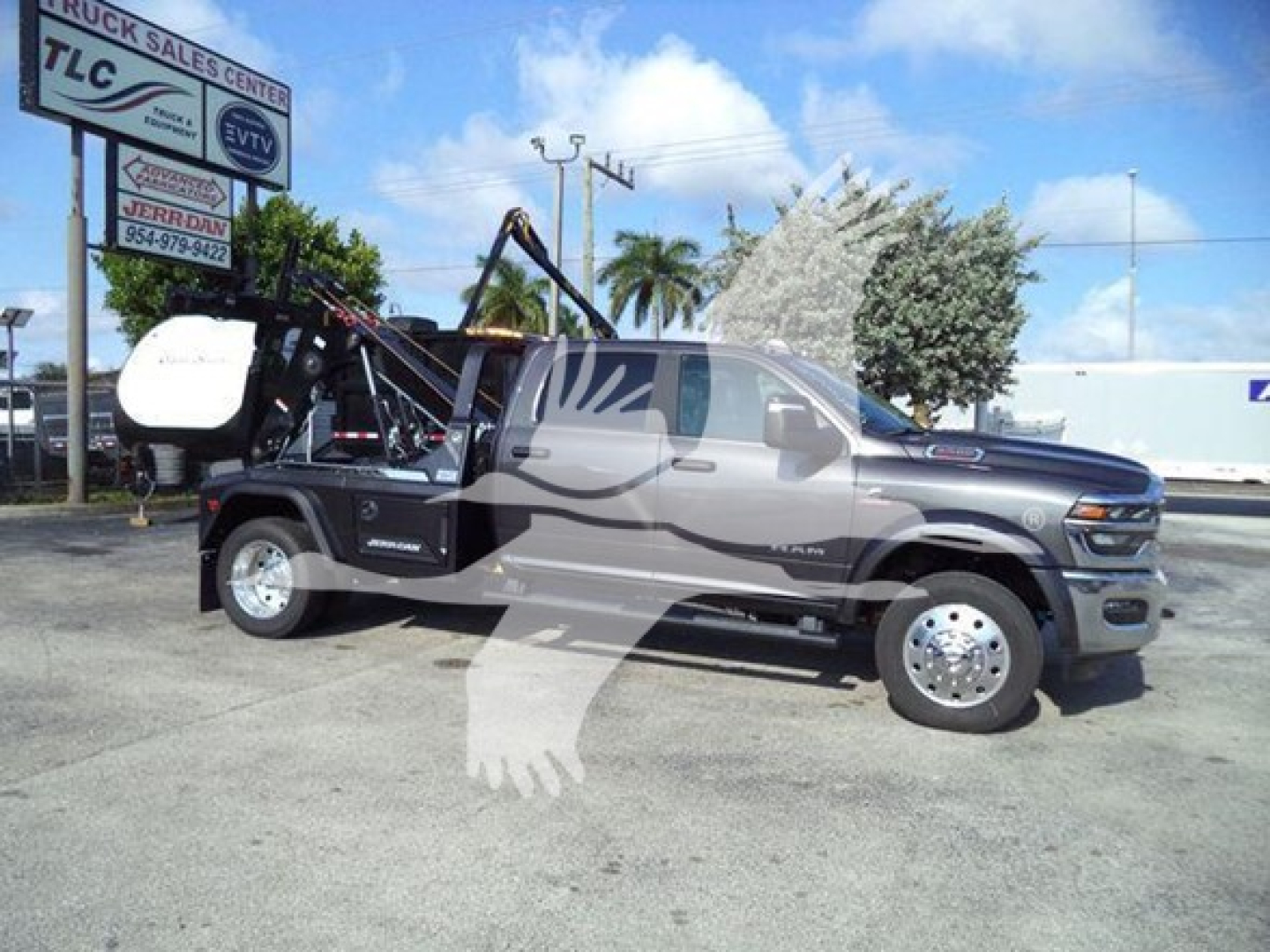 Ram pickup truck in showroom/lot with winch equipment attached at rear, side view showing crew cab, chrome wheels, and hydraulic crane assembly.