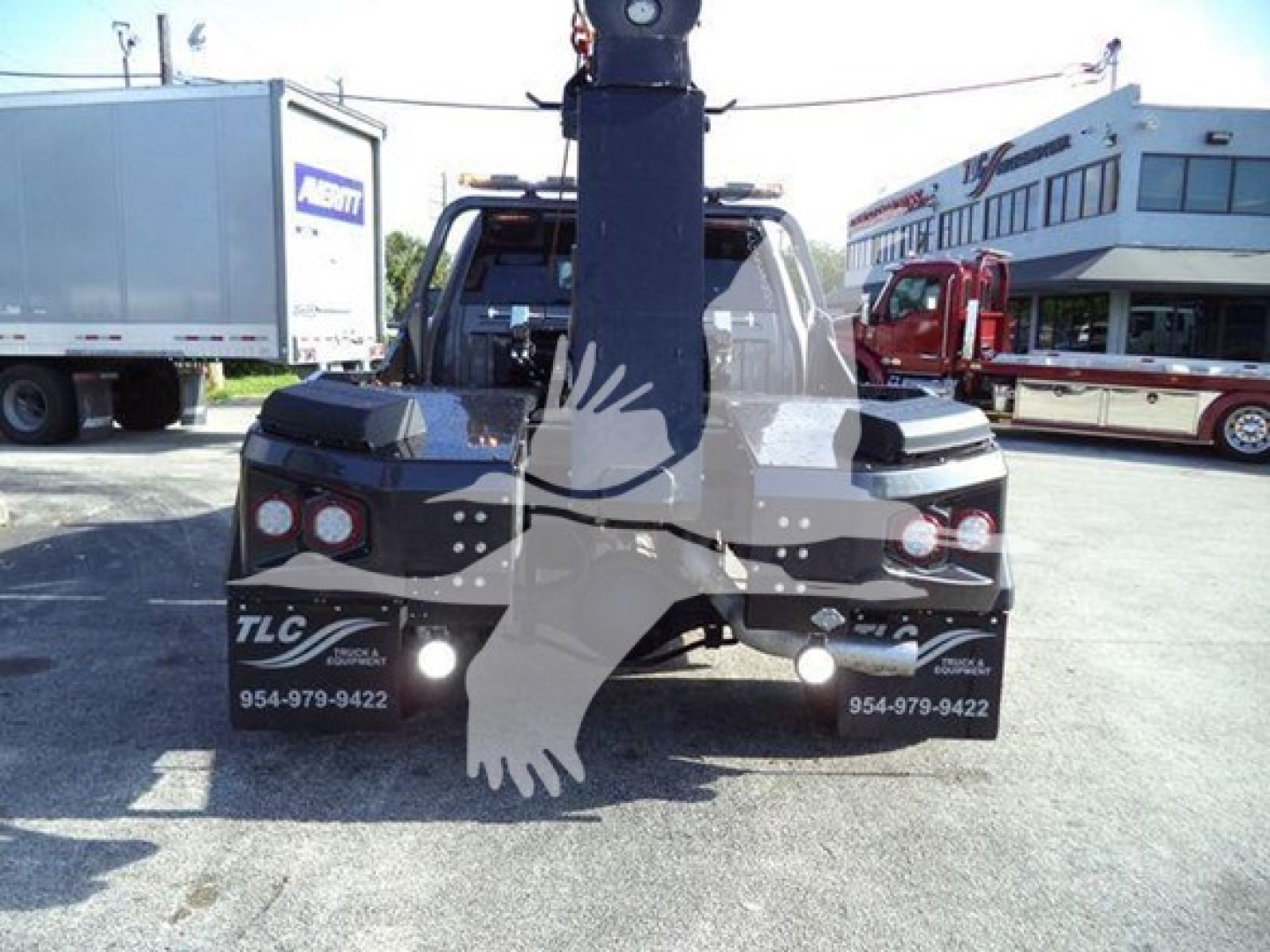Winch-equipped Ram pickup back view showing heavy-duty crane and tow hitch with rear lights, dealership lot in background.
