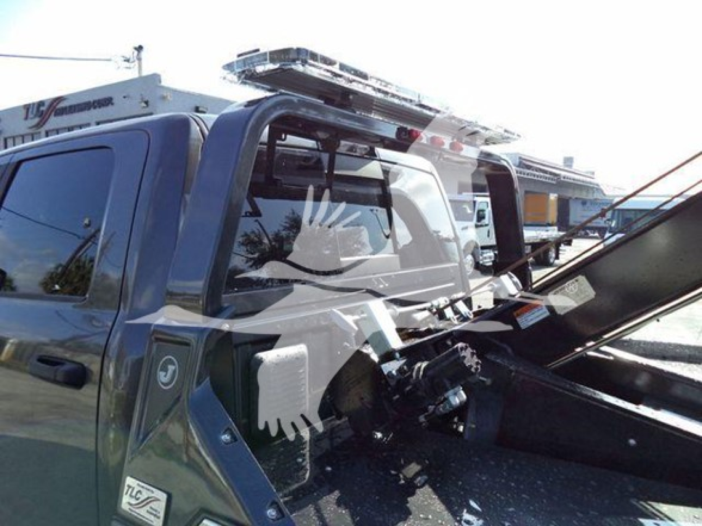 Ram pickup truck cabin with winch equipment visible in bed, front window reflection, and roof rack.