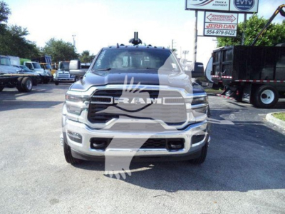 Truck front view showing RAM grille emblem and large chrome bumper with fog lights; dealership lot in background.