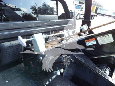 Winch system mounted in truck bed showing mechanical cable winch with protective housing and mounting hardware.