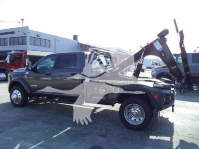 Ram pickup truck with a winch and tow equipment in a dealership lot. Visible text on vehicle includes RAM and 2500 series badge.