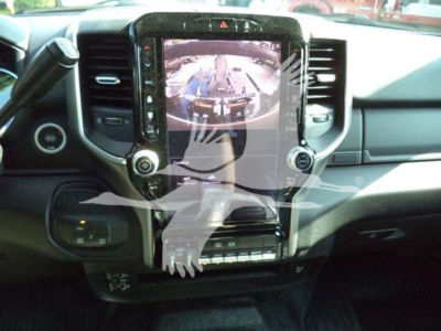 Dashboard view of a RAM pickup with large touchscreen display and gear shifter, interior center console visible.