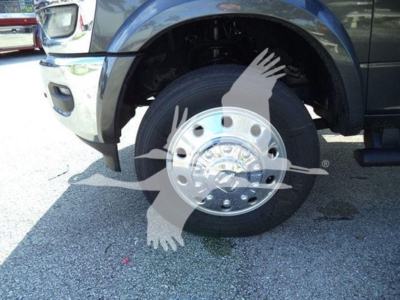 Truck front wheel and fender showing chrome hub with center bolts and tire tread, partial front bumper visible.