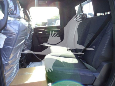 Truck interior showing second row seat and door panel; protective plastic on seats. Windows reveal sunny outdoor lot.