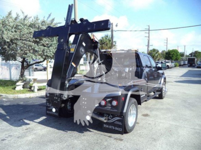 Truck with a large fork-lift style attachment lifting vertically at the rear, towing/flatbed with chrome wheels. Visible text on rear fender and bumper: area codes and contact numbers; no clear model text readable.