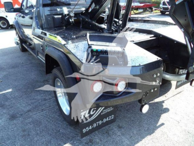 Ram pickup truck with a winch and open bed showing accessories and decals. Visible text includes VIN tag on windshield area? No, main visible text: '954-979-9422' on a black mudflap/plate at rear. Some chrome bumper, and truck bed equipment