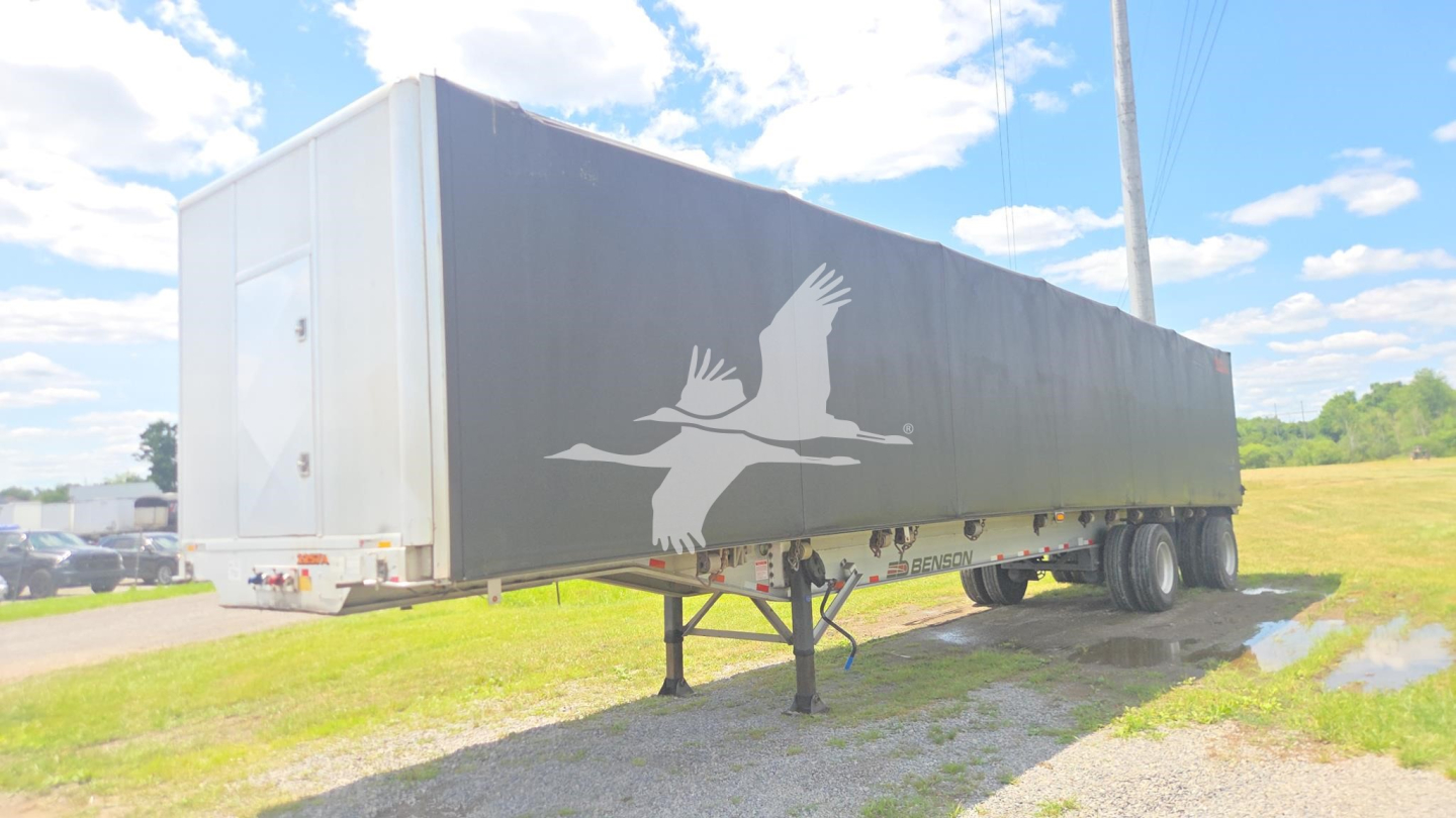 Conestoga flatbed trailer showing side graphic of flying birds and a rain of rust? No—graphic text not legible.