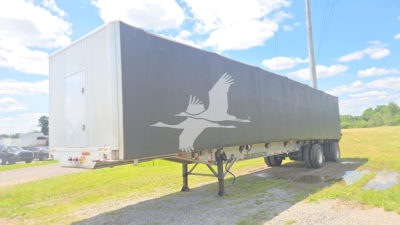 Conestoga flatbed trailer showing side graphic of flying birds and a rain of rust? No—graphic text not legible.