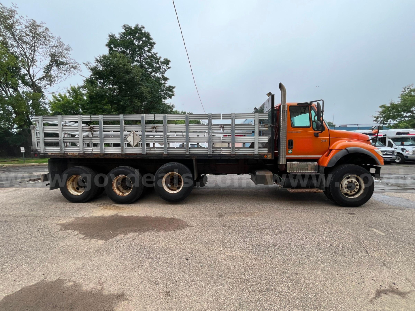 2004 International 7600 flatbed dump truck side view showing long aluminum stake-bed and orange cab