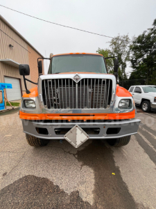 Front view of a 2004 International 7600 flatbed dump truck showing radiator grille, headlights, and front bumper.