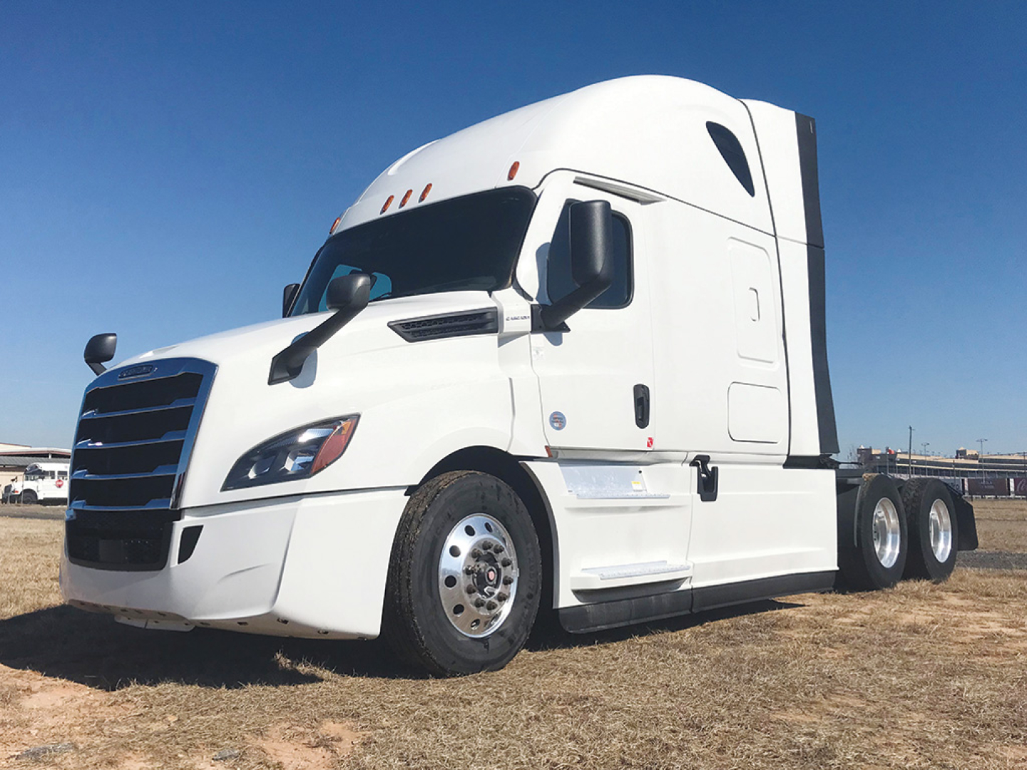 Truck: 2022 Freightliner Cascadia 126 conventional sleeper, white, side view showing cab with sleeper, front grille, headlamps, and dual rear axles.