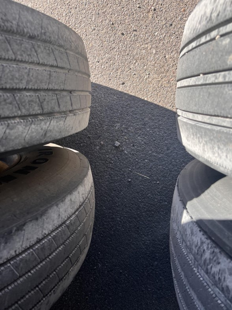 Tires arranged in a stack with asphalt ground visible between them.