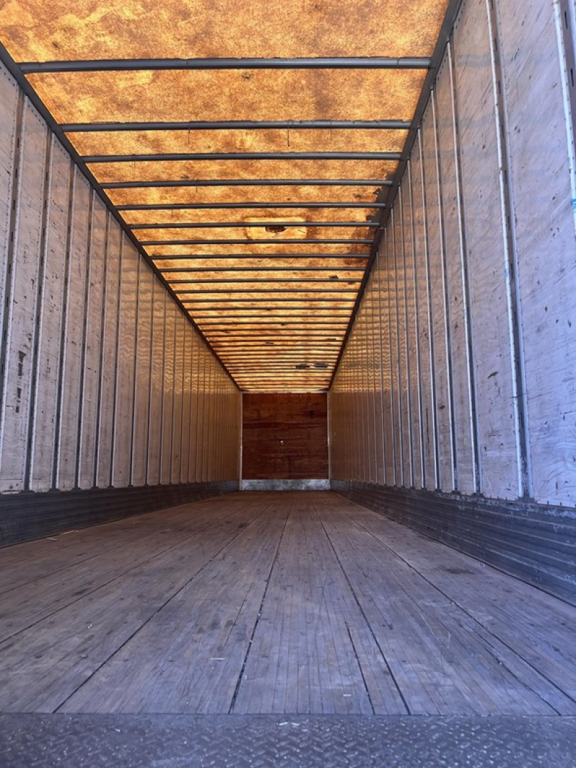 Trailer interior showing long empty cargo area with wooden floor and metal side walls.
