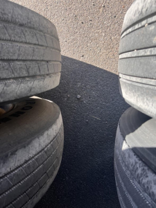 Tires arranged in a stack with asphalt ground visible between them.