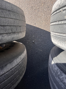 Trailer tires stacked in a narrow gap showing worn tread on all four tires surface.