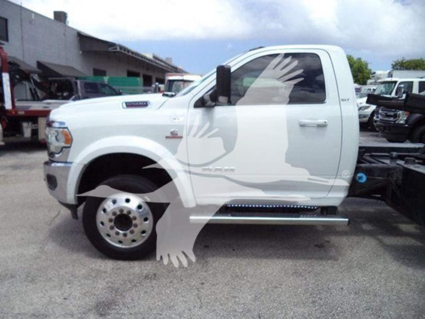 Truck side view showing a white 2021 Ram SLT with extended cab, rollback equipment in lot.
