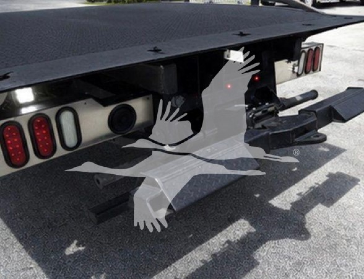 Rear view of a Ram rollback truck showing taillights, hitch, and flatbed with support beams.