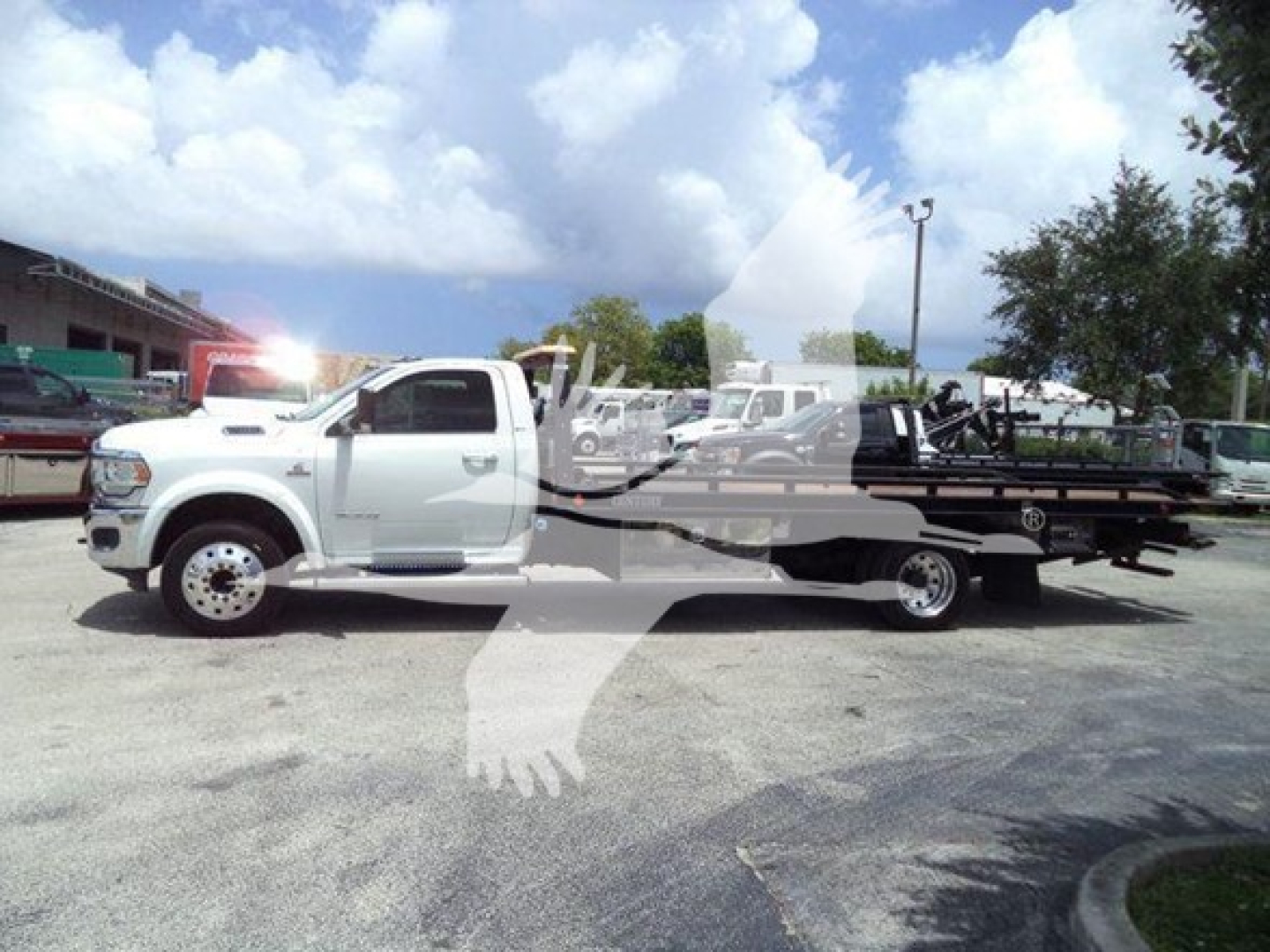 Ram 2500/3500 tow truck with rollback bed, white cab, side view showing VIN sticker and stock number in lot.