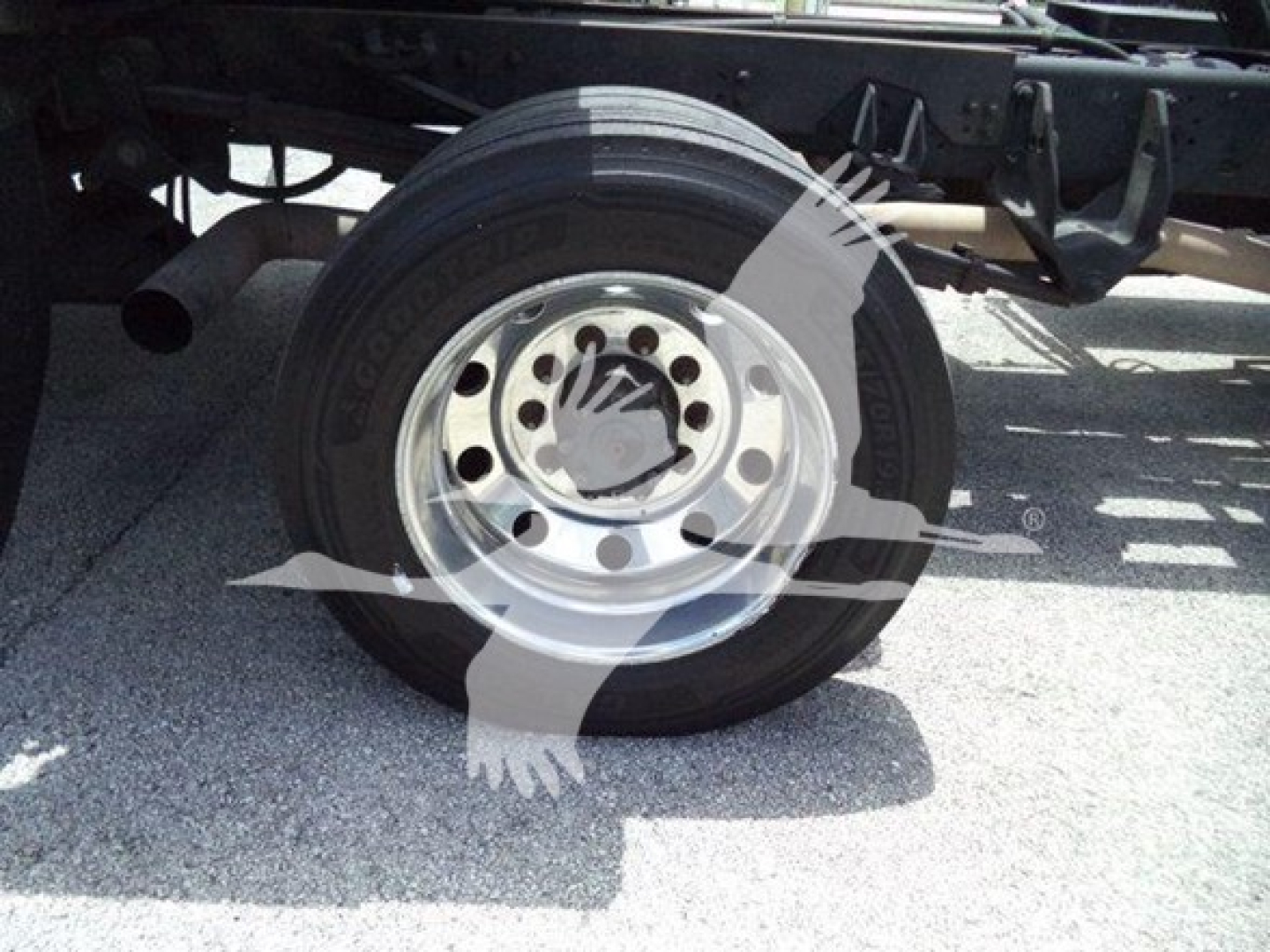 Truck wheel and suspension visible with Goodyear tire and steel rim, partial undercarriage. Overlay watermark image.