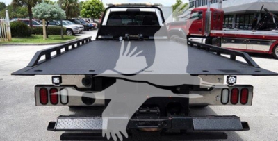 Ram pickup truck rollback bed with flatbed and wheel chocks, rear view showing taillights and hitch, 2021 Ram SLT used vehicle.