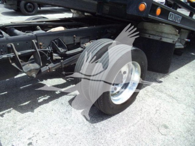 Truck chassis rear wheel and suspension visible under 2021 Ram SLT rollback truck, vehicle frame with spare wheel area and underbody components.