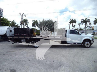 2021 Ram SLT roll-back truck side view showing white cab with flatbed and equipment in bed.