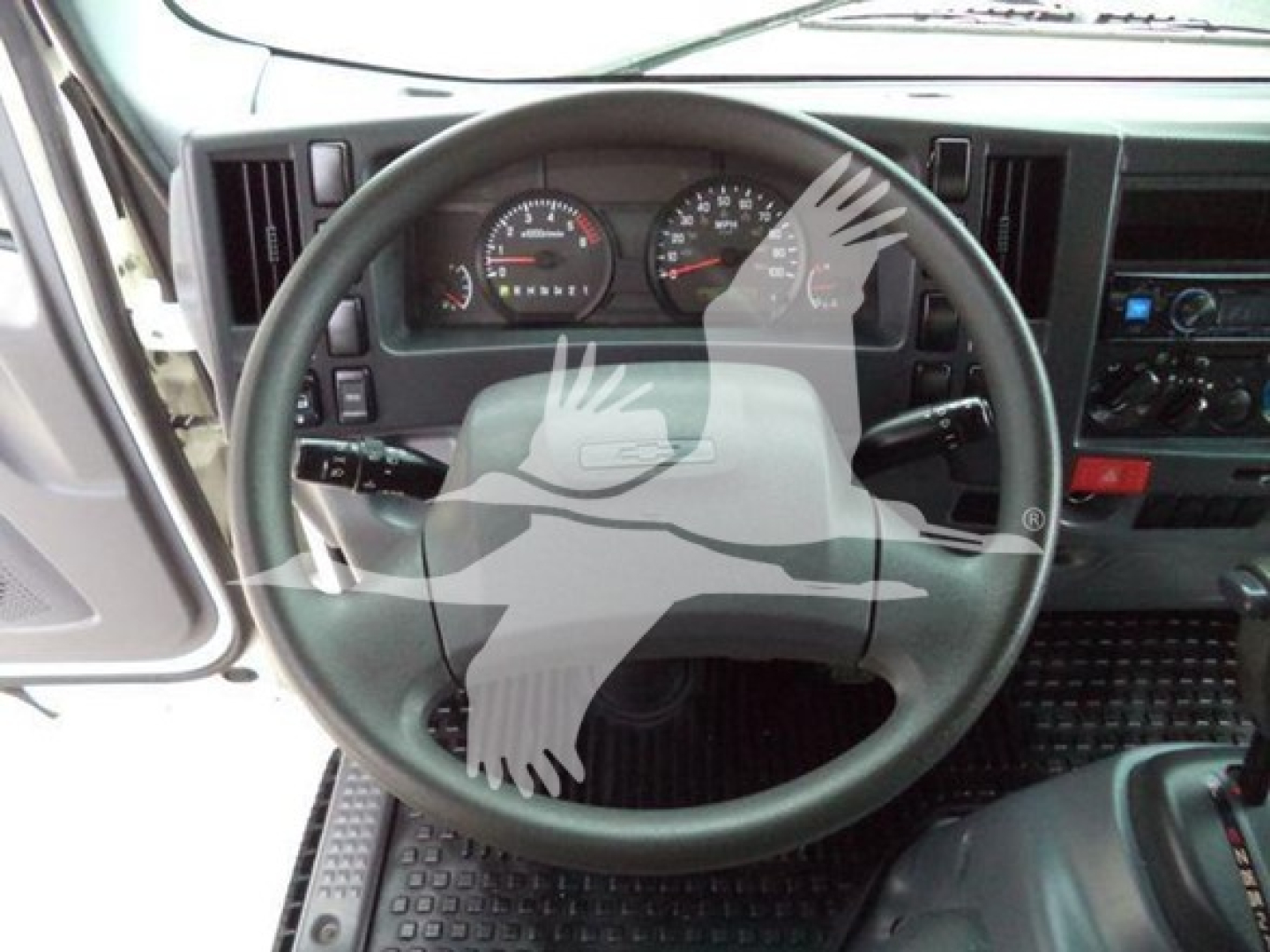Truck dashboard steering wheel and gauges with gray watermark overlay. Visible text on dashboard includes speedometer, tachometer, and control panel faintly readable. 