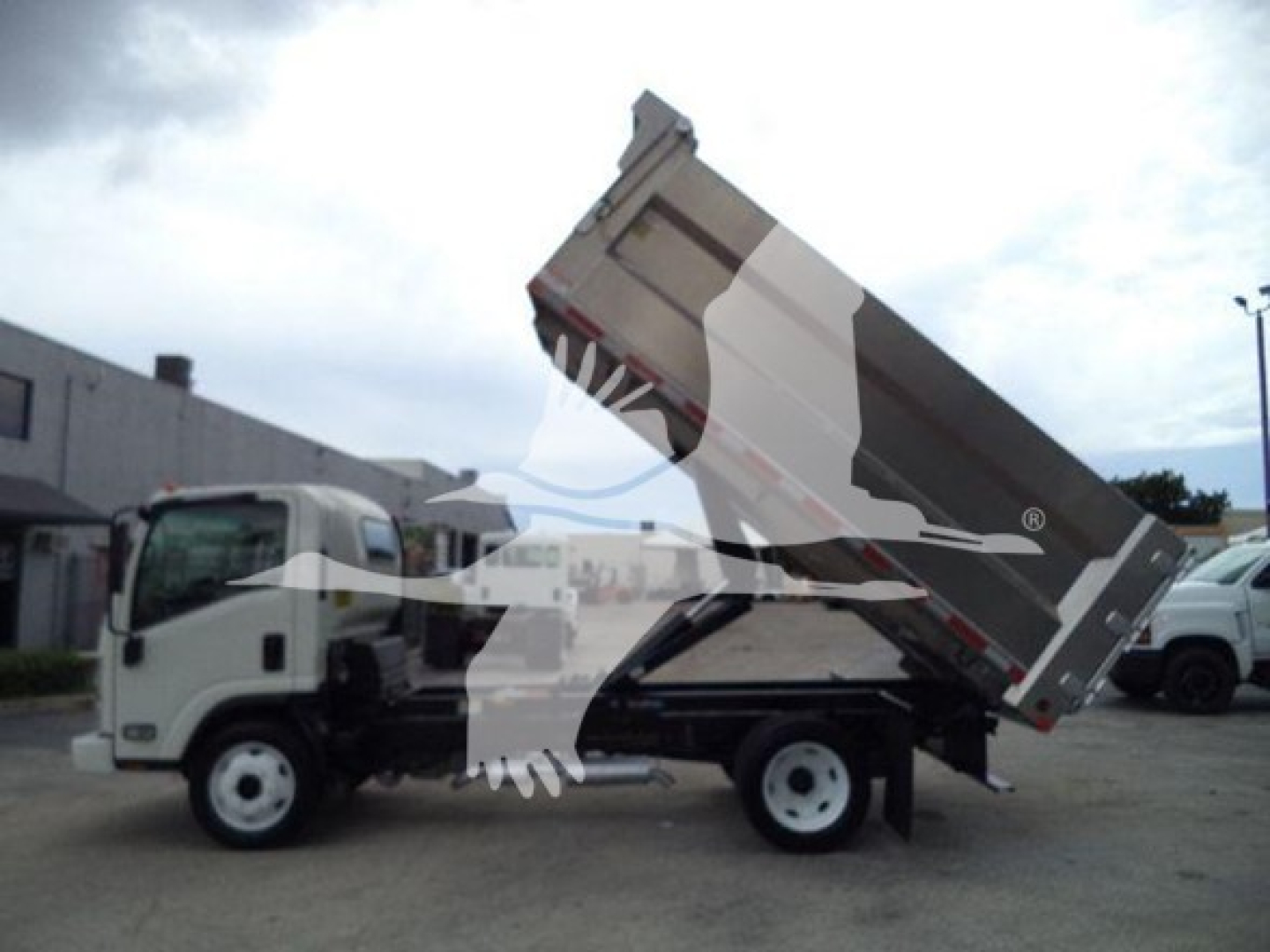 Dump truck with raised bed on a Chevrolet W4500 chassis showing cargo bed and hydraulic lift mechanism.