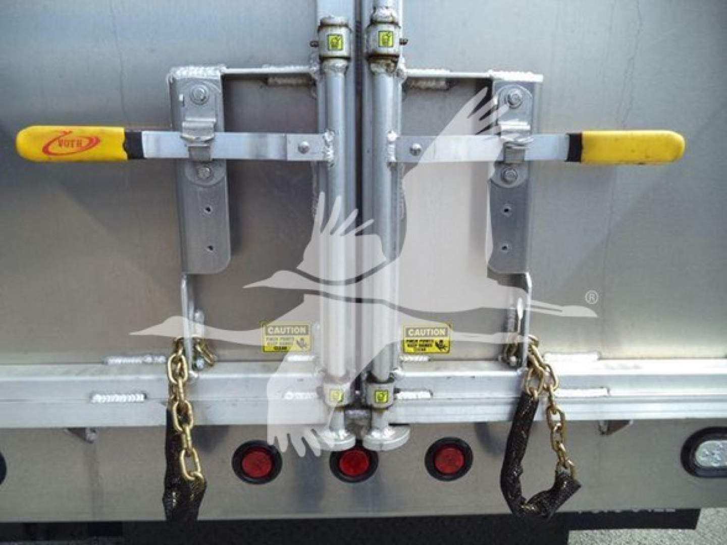 Back of Chevrolet W4500 dump truck showing dual latches with yellow handles and rear door hardware, chains hanging, and taillights visible.