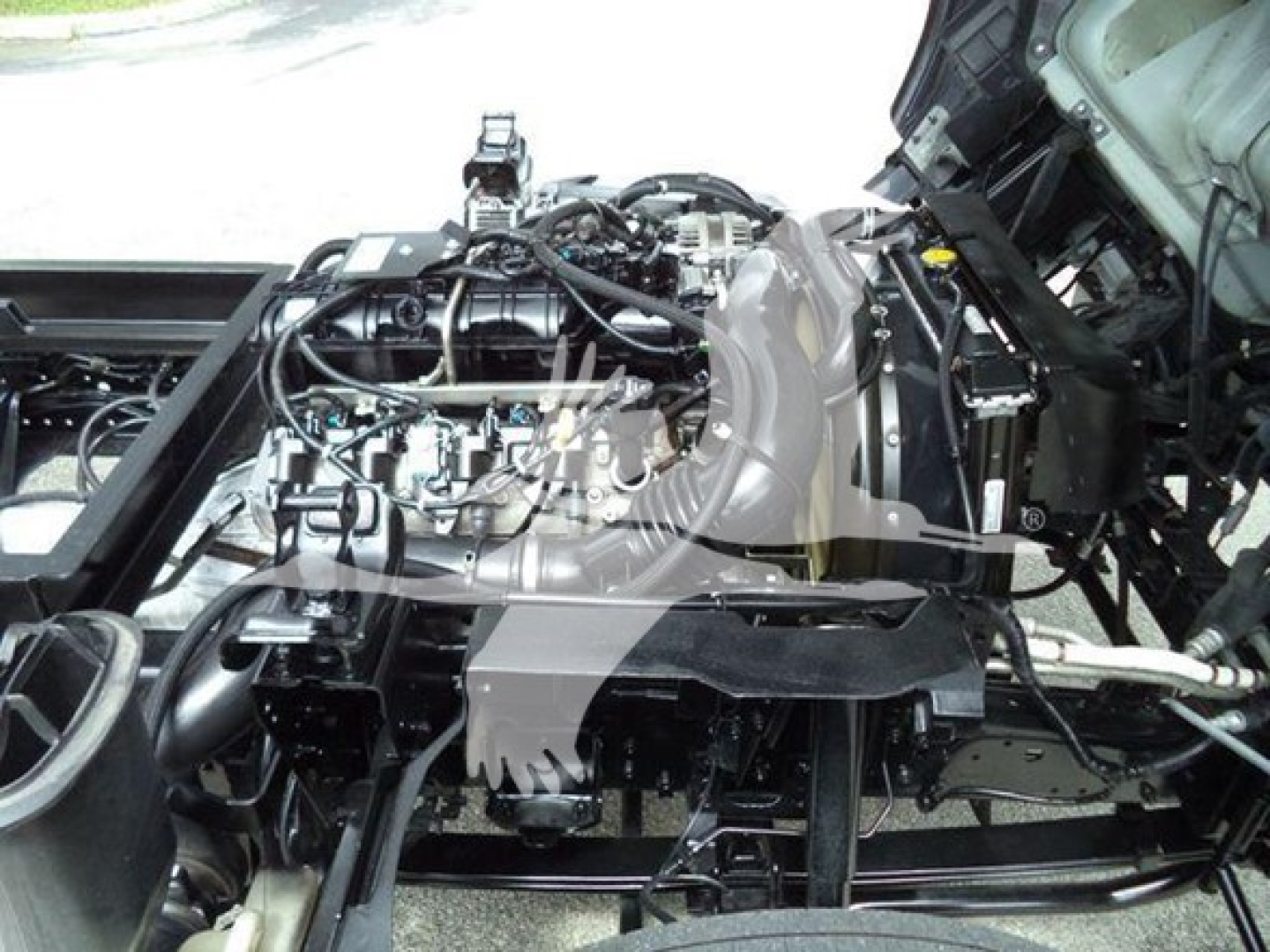 Chevrolet W4500 truck engine bay with exposed mechanical components and wiring, showing the engine, intake manifold, and surrounding frame.