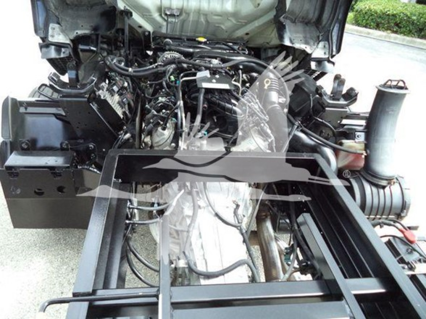 Chevrolet W4500 engine bay with exposed components and wiring, front chassis frame visible, various hoses and a large air intake tube.