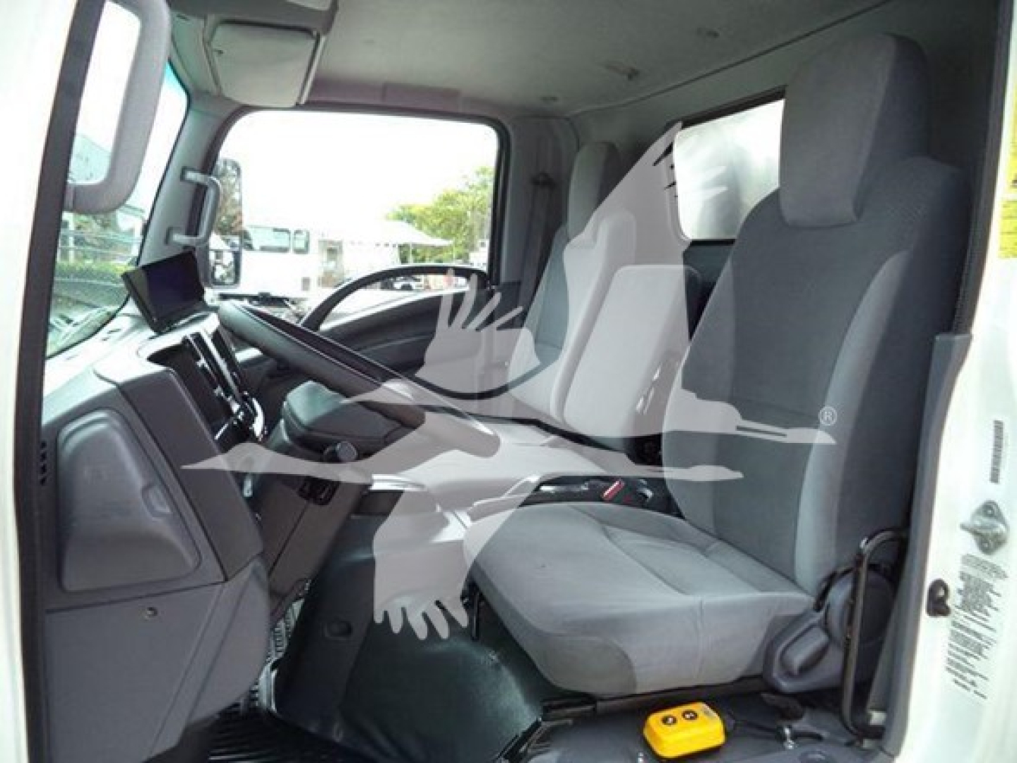 Cab interior of a Chevrolet W4500 truck showing driver and passenger seats, steering wheel, dashboard, and a tablet/monitor mounted on the dash.