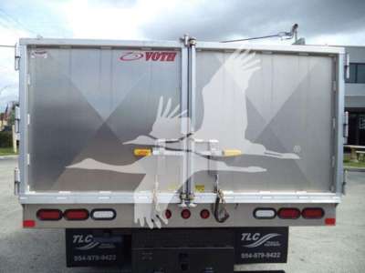 Rear view of a GMC/Chevrolet W4500 dump truck with twin barn doors featuring a large white bird graphic, VOTH brand sticker, and multiple tail lights.