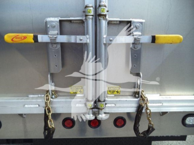 Back of Chevrolet W4500 dump truck showing dual latches with yellow handles and rear door hardware, chains hanging, and taillights visible.