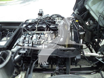 Chevrolet W4500 truck engine bay with exposed mechanical components and wiring, showing the engine, intake manifold, and surrounding frame.