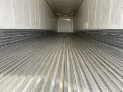 Trailer interior empty refrigerated trailer cargo area with ribbed floor and white walls, rear door visible at end.