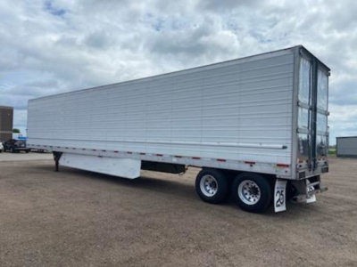 Utility reefer trailer side view showing tandem axle with white exterior and rear doors.