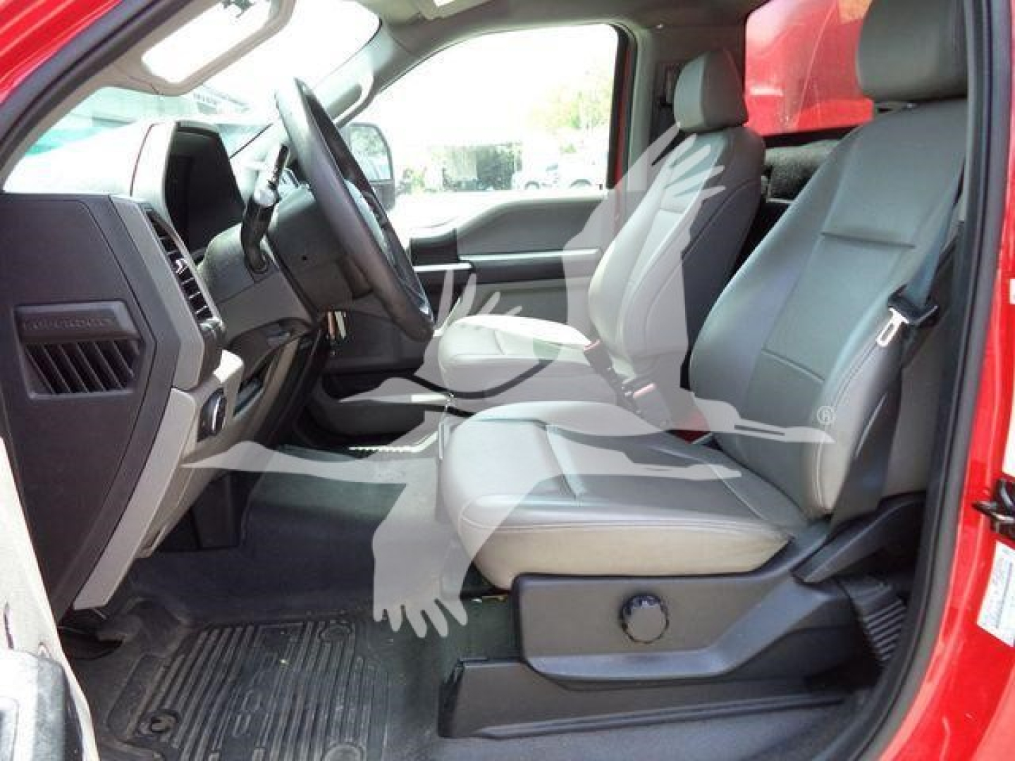 Front interior of a red 2020 Ford F-550 cab showing grey vinyl seats, steering wheel, and driver-side door; visible floor mats and seat controls.