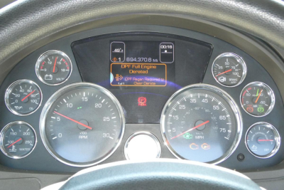 Dashboard of a Kenworth truck showing instrument cluster with multiple gauges and a central digital display reading 'DPF full engine derated' and 'DEF System' warnings.