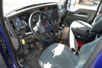 Kenworth T680 cab interior showing steering wheel, dashboard gauges, gear shifter, and driver seat with controls.