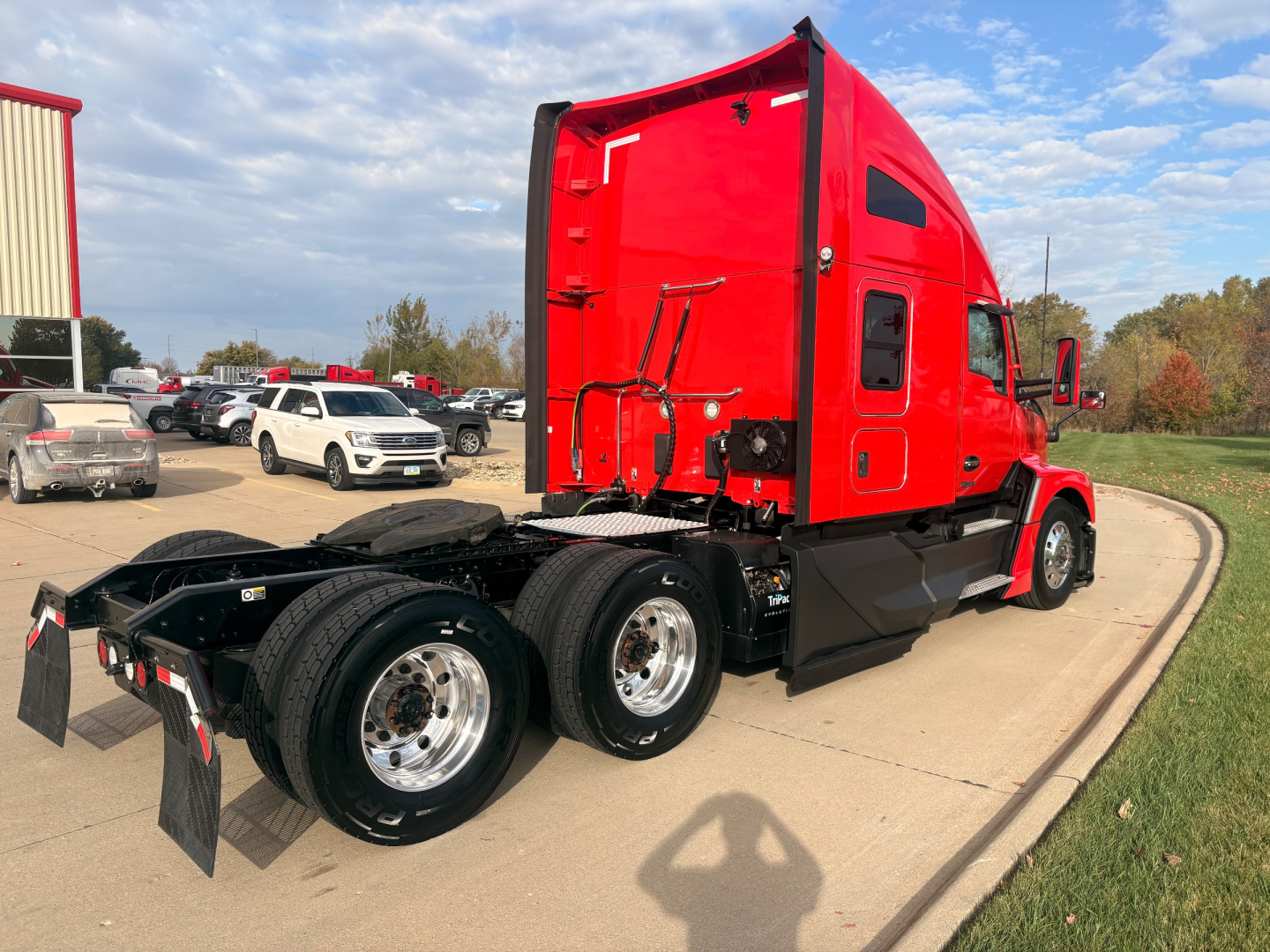 Kenworth T680 tractor side rear showing red sleeper cab and dual rear axles with chrome wheels.